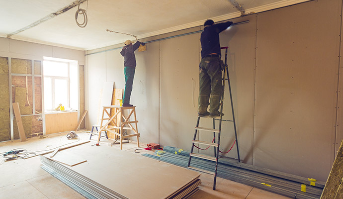 Workers installing drywall during reconstruction