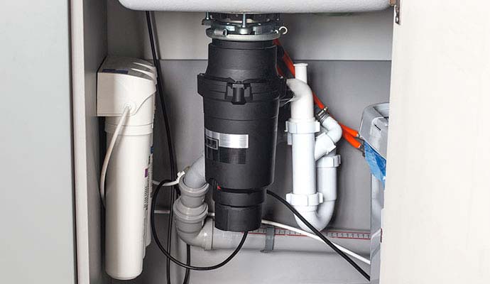 Garbage disposal unit and water filtration system under a kitchen sink cabinet