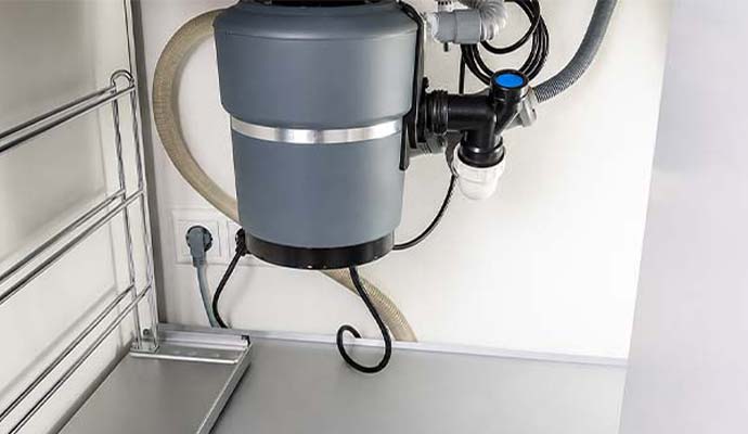 Garbage disposal unit with drain plumbing connections installed under a kitchen sink