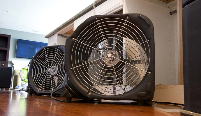Industrial air movers drying hardwood flooring and kitchen cabinets after water damage