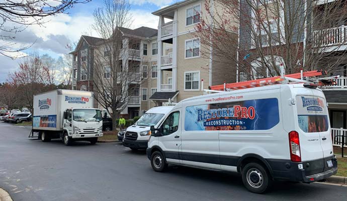 RestorePro Reconstruction service vans and truck parked outside an apartment complex