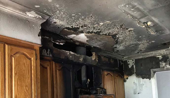 Burned kitchen cabinets and charred ceiling after a structural fire damage