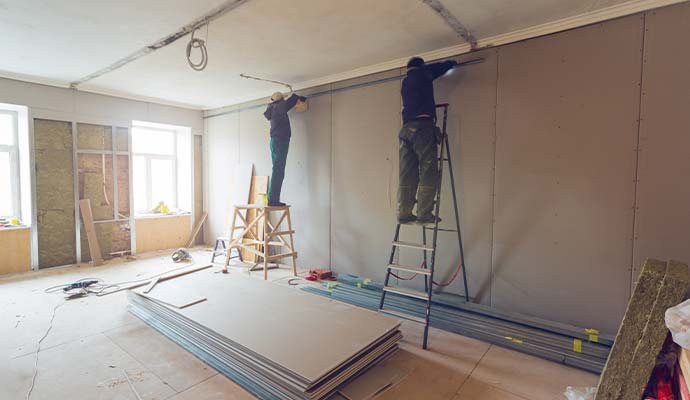 Construction workers installing drywall during property reconstruction