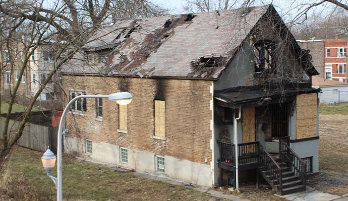 Fire-damaged house with plywood board up on windows and roof