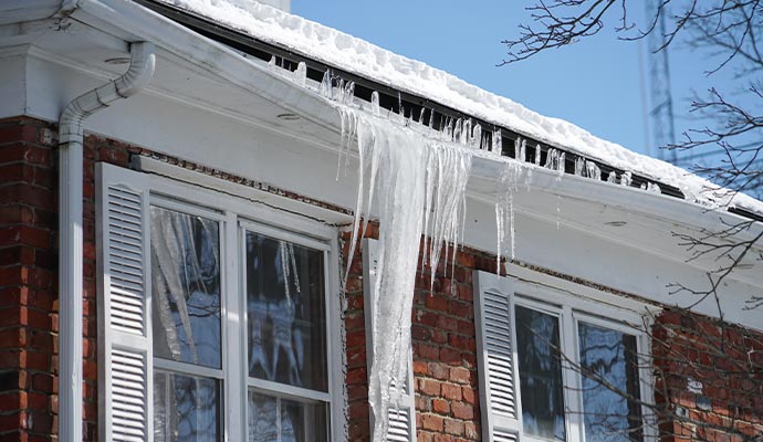 Heavy icicles and ice dams forming on a residential gutter system