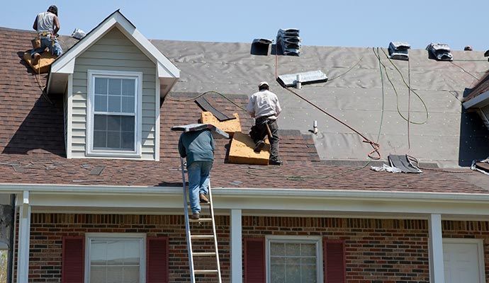Roofing crew installing new asphalt shingles on house
