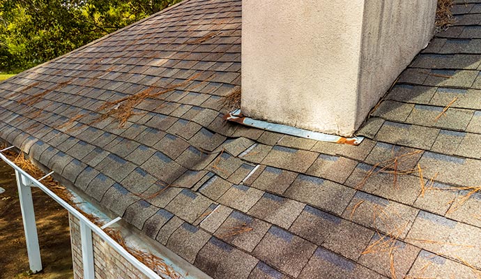 Damaged roof shingles near chimney