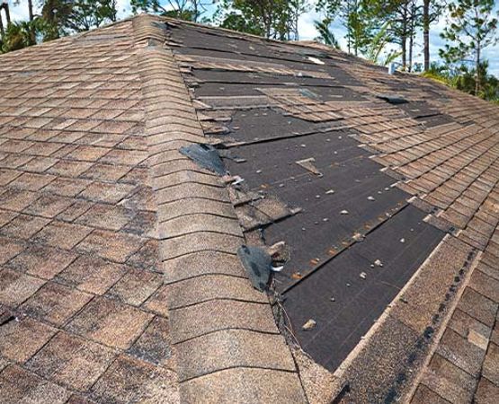 A residential roof with significant wind damage and missing shingles